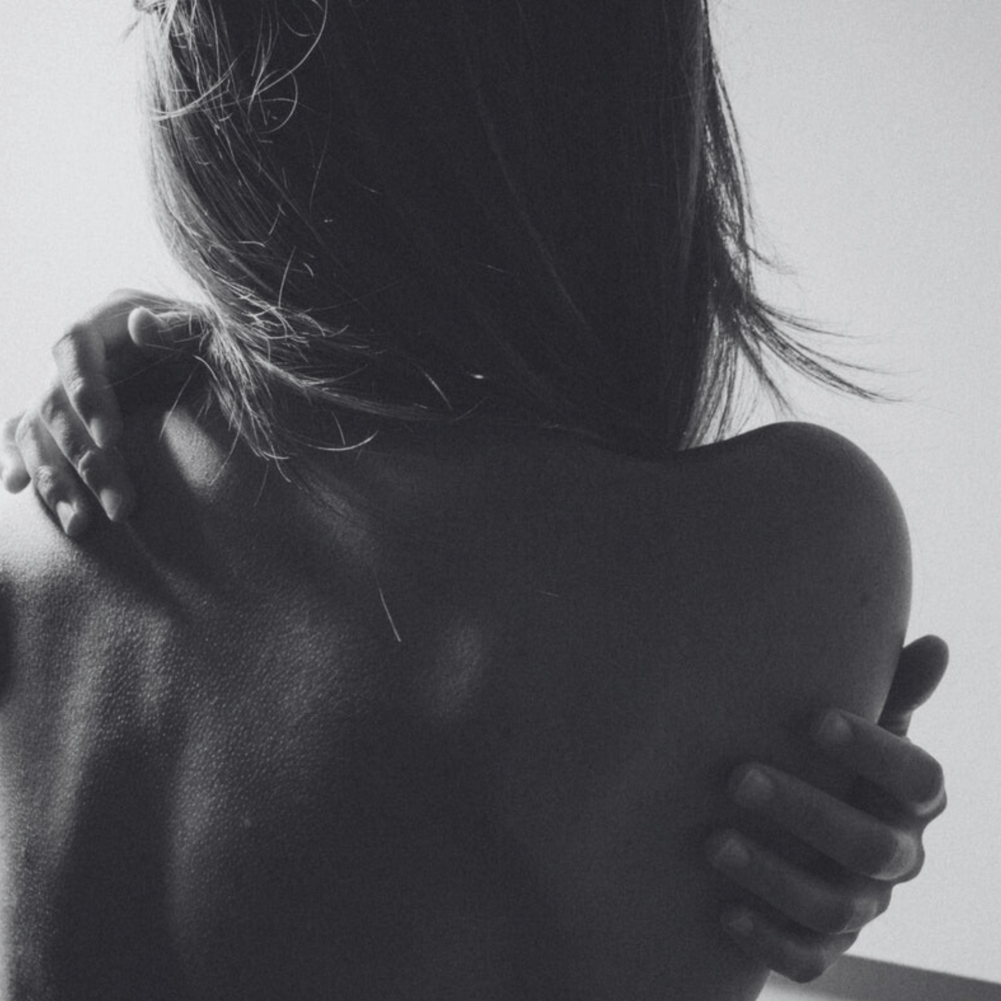 Black and white photo of a person embracing another from behind