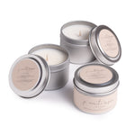 Four travel-size candle tins with lids, each featuring a burning candle. The tins are silver with a label that reads 'affirmation', and each has a different scent name underneath.