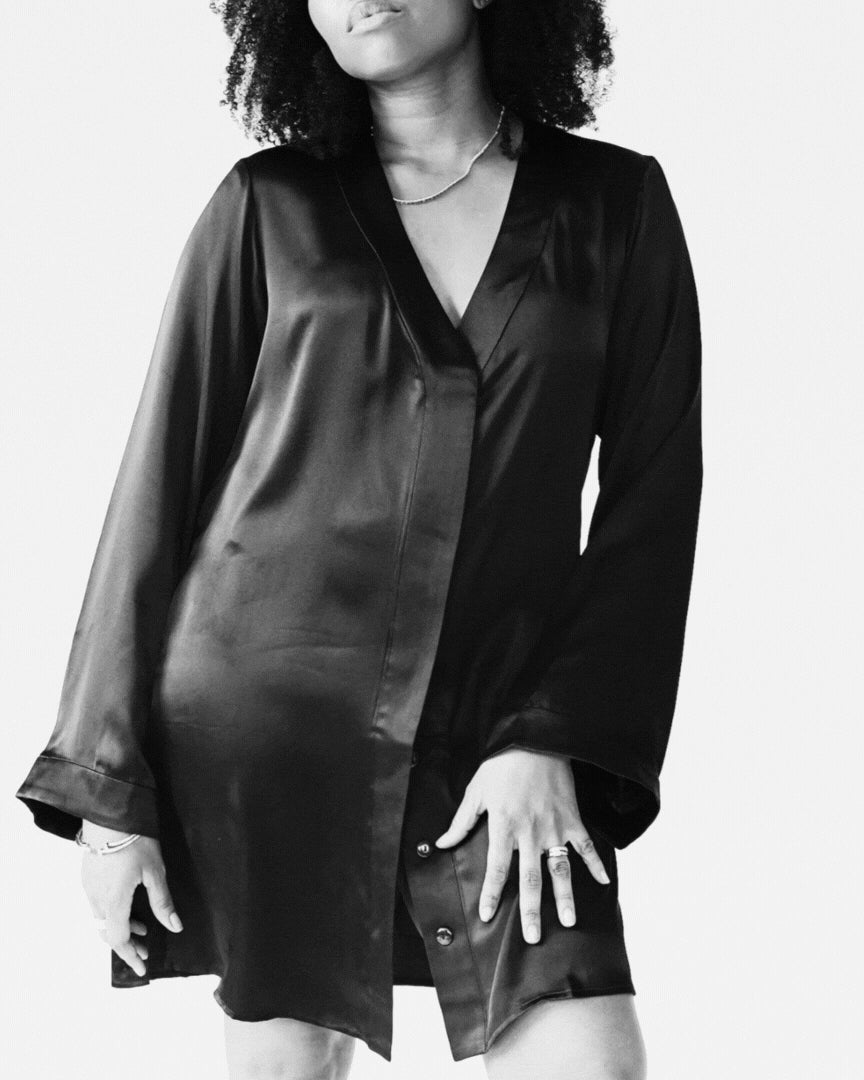 Person wearing a black satin shirt against a white background