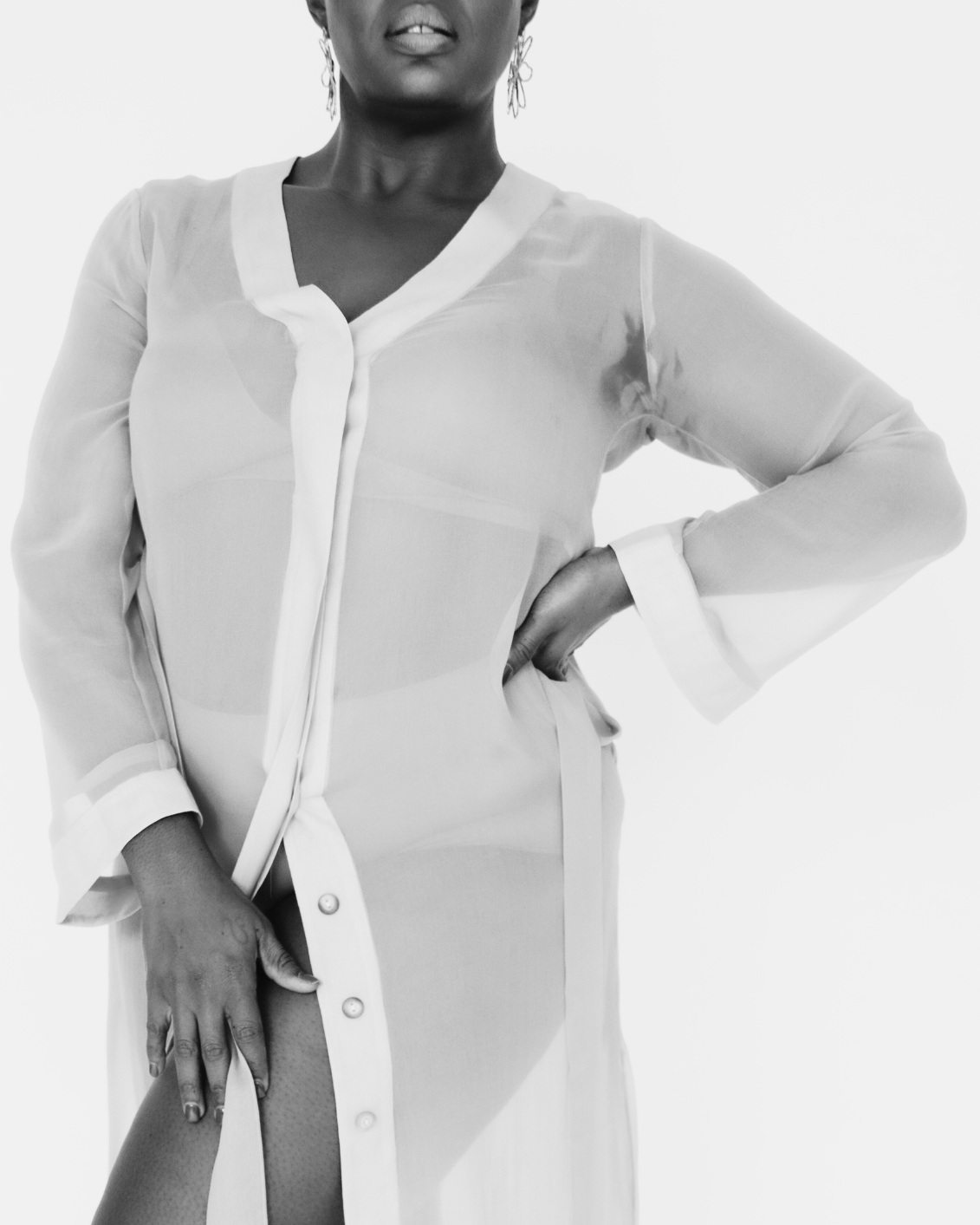 Person wearing a long, light-colored cardigan with a plain background