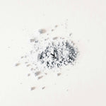 Small clock embedded in a pile of white powder on a white background