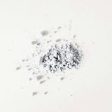 Small clock embedded in a pile of white powder on a white background
