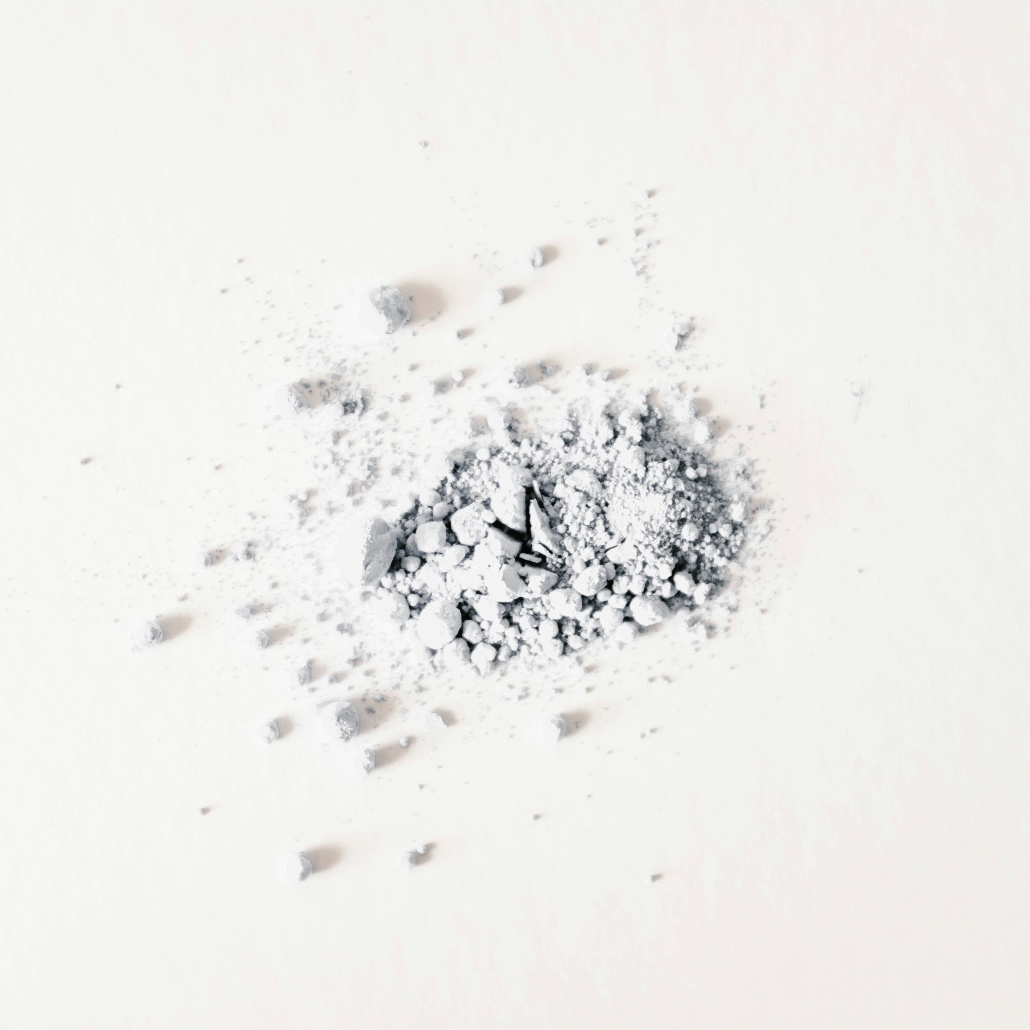 Small clock embedded in a pile of white powder on a white background