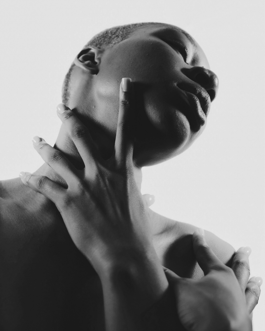 Black and white photograph of a person with hands on face against a plain background