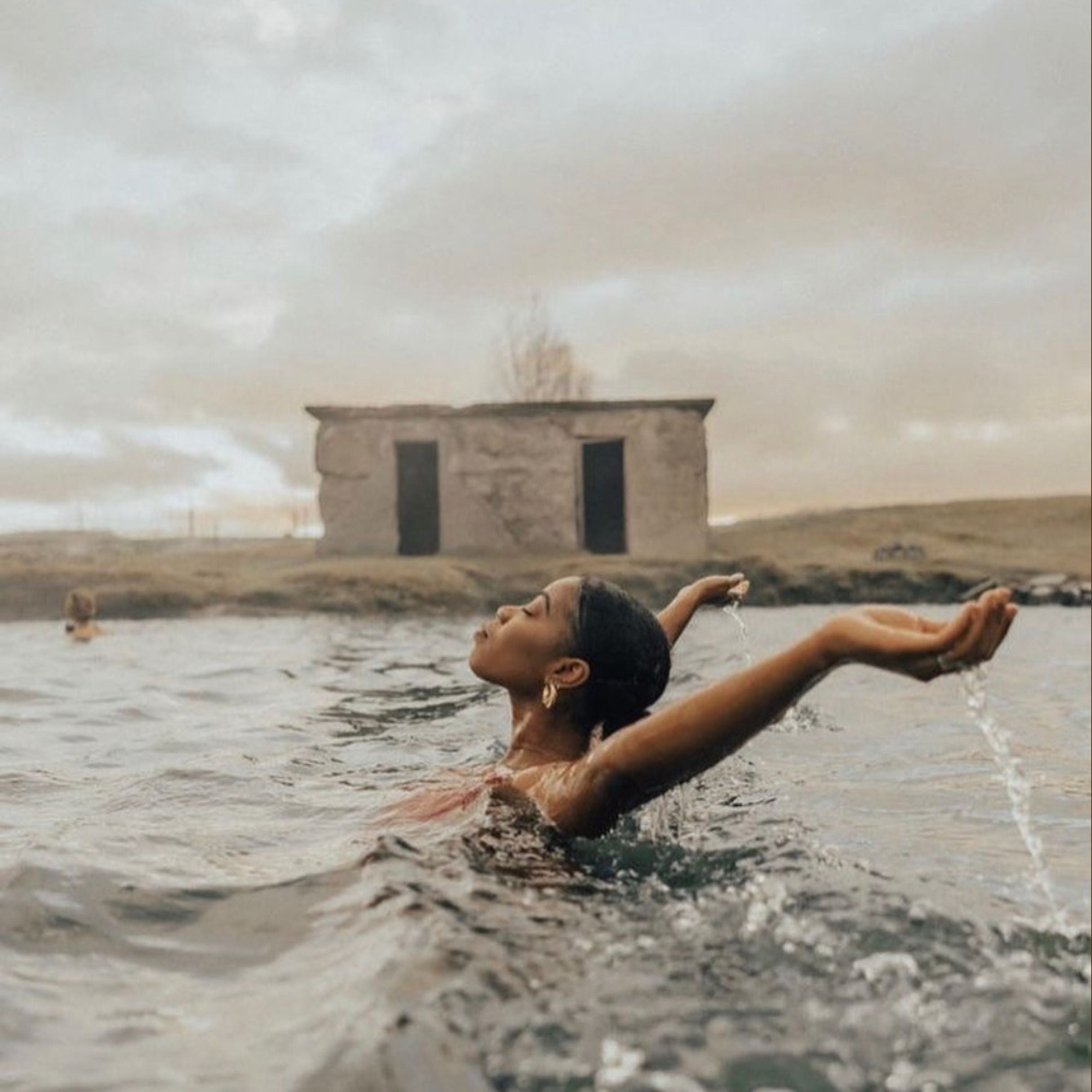 Person swimming in a body of water with a building in the background
