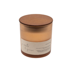 A jar candle with amber-colored wax in a translucent glass container, featuring a round wooden lid and a beige paper label with handwritten-style text, shown on a plain white background.