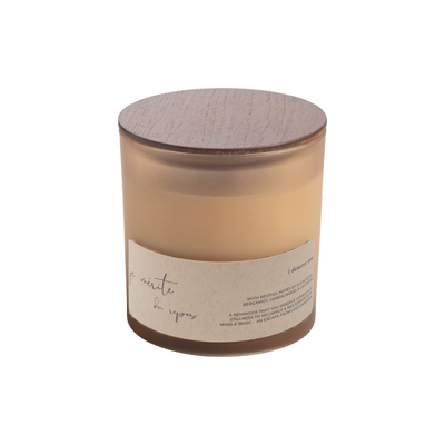 A soy candle in a frosted glass jar with a light brown wooden lid and a beige paper label, shown on a plain white background.