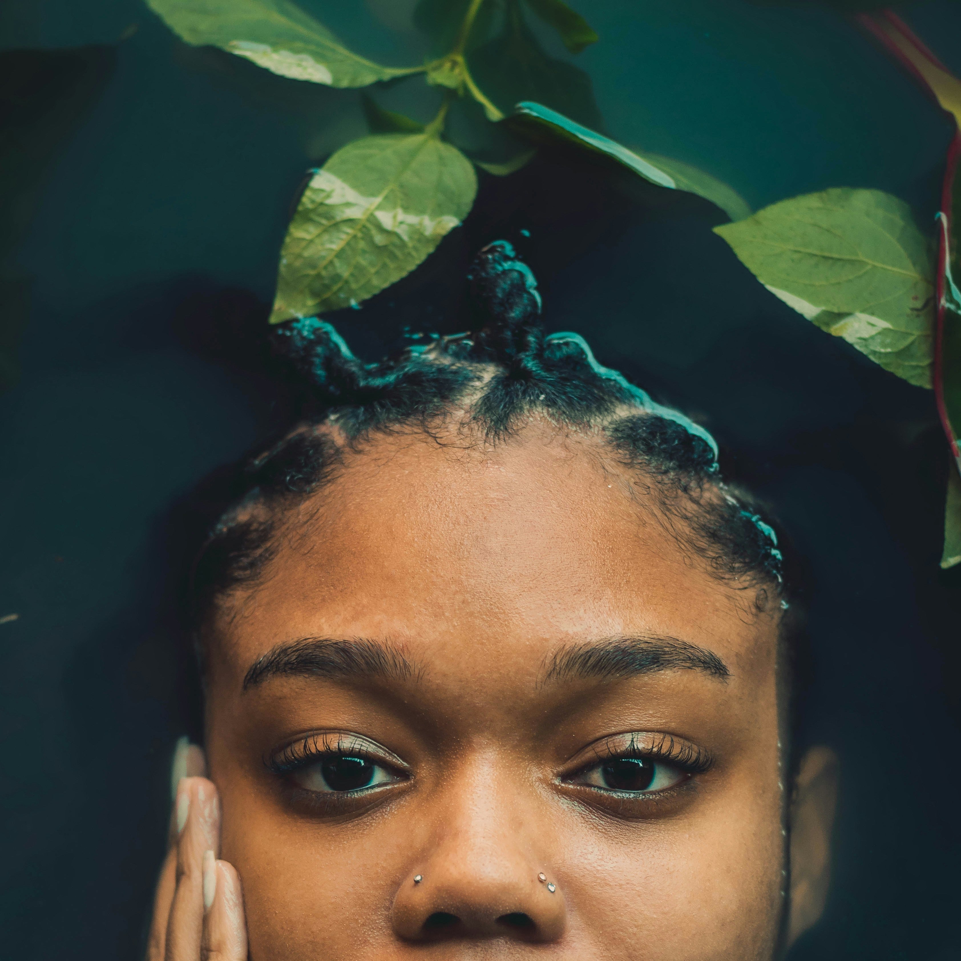Woman with braided hair and green leaves in the background