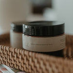 Jar of body butter on a woven tray with a blurred background