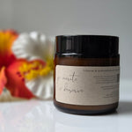 Jar with a label on a white surface with flowers in the background