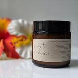 Jar with a label on a white surface with flowers in the background