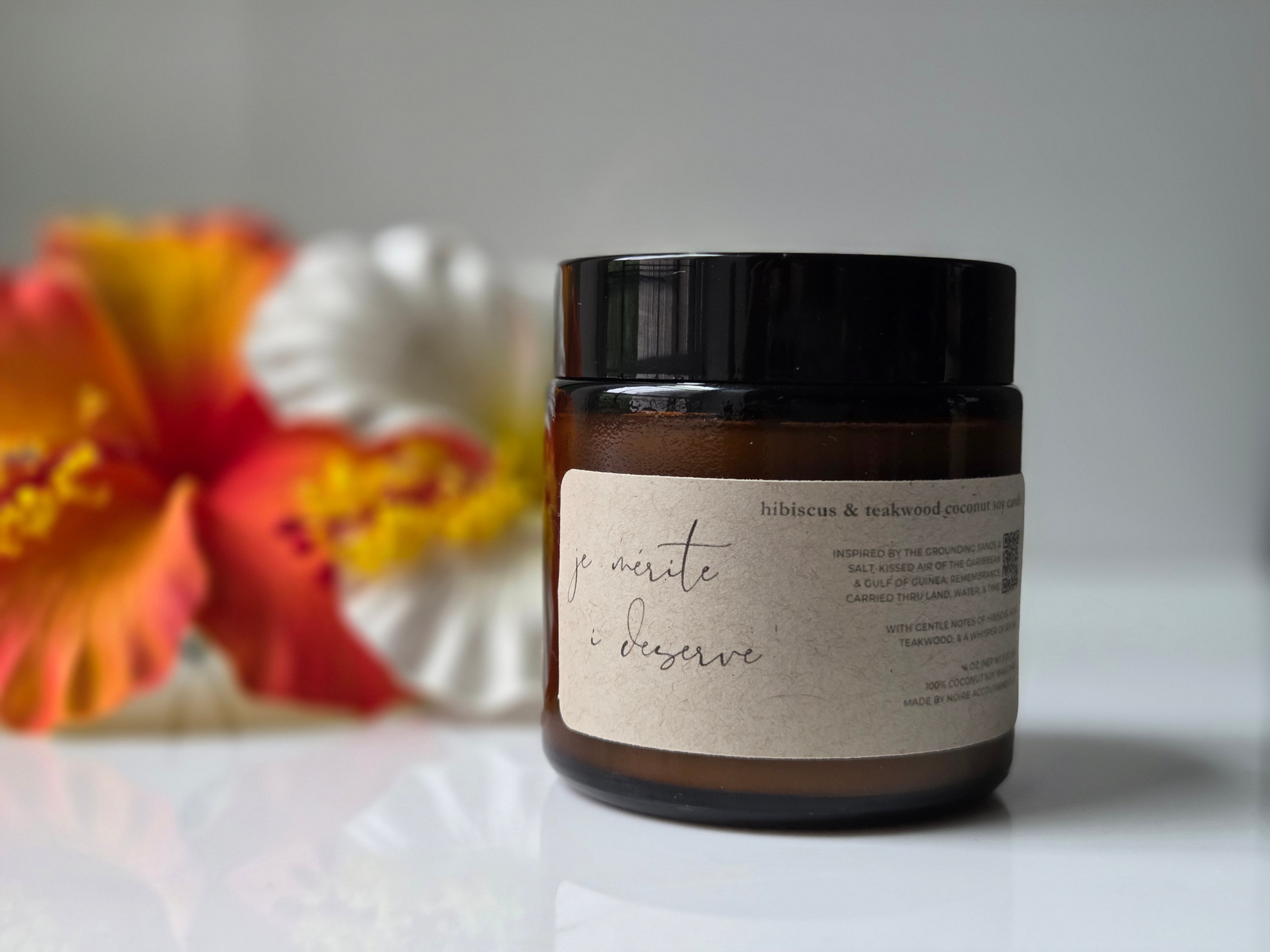 Jar with a label on a white surface with flowers in the background