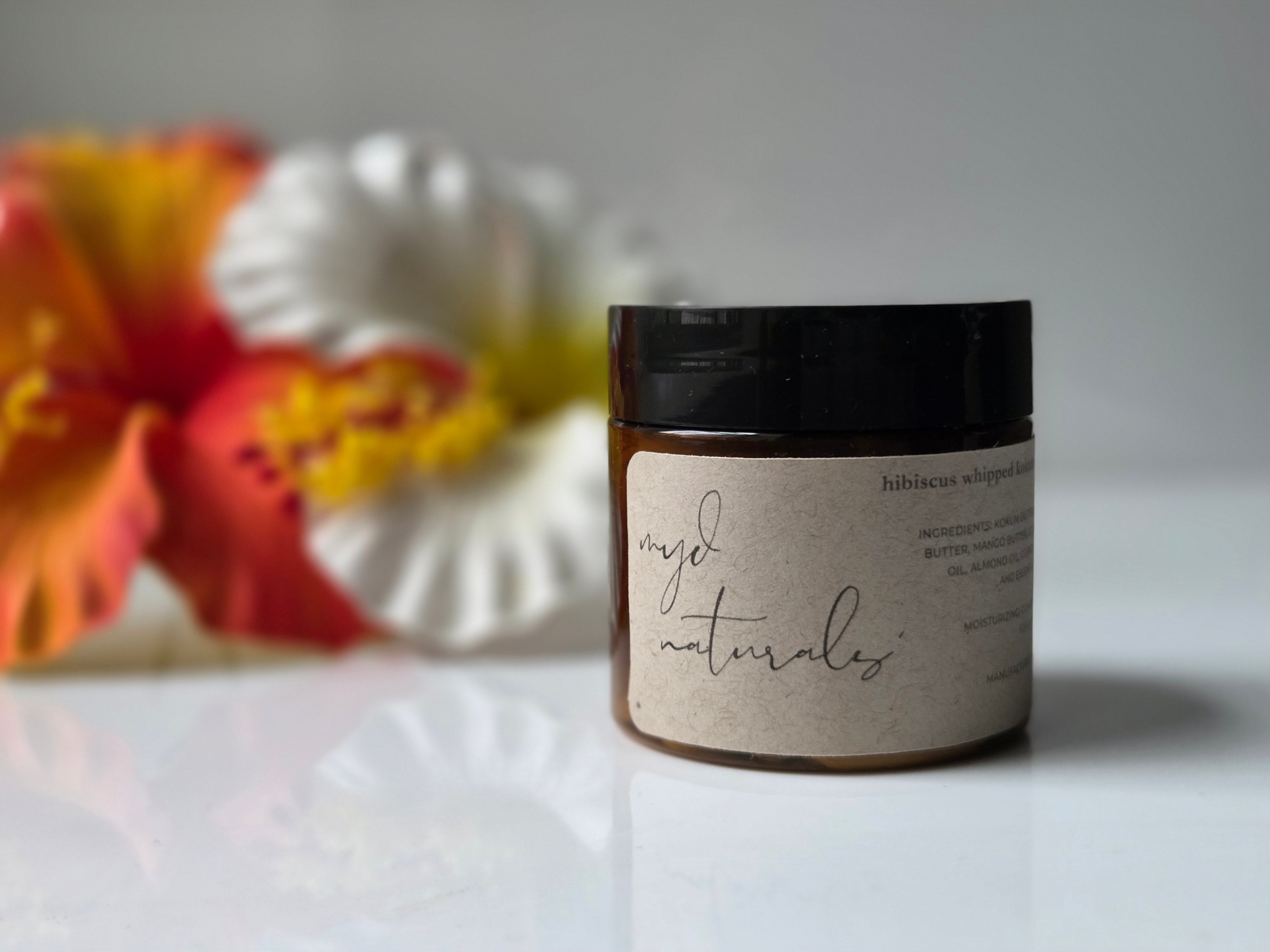 Jar of 'myd naturals' product with flowers in the background