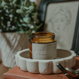 Candle in an amber jar on a decorative stone holder with a blurred background