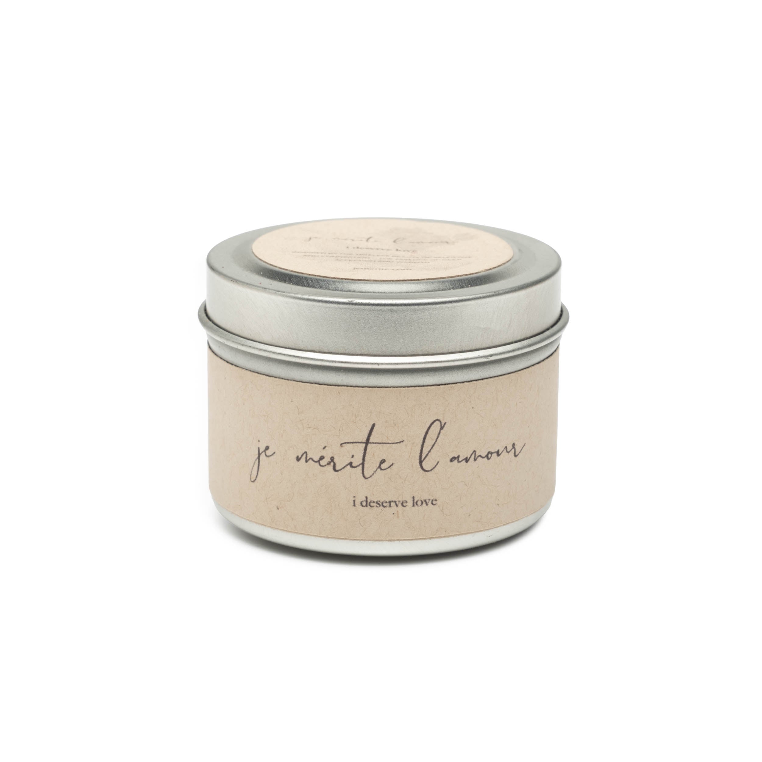 Candle in a tin with 'je mérite l'amour' text on a white background