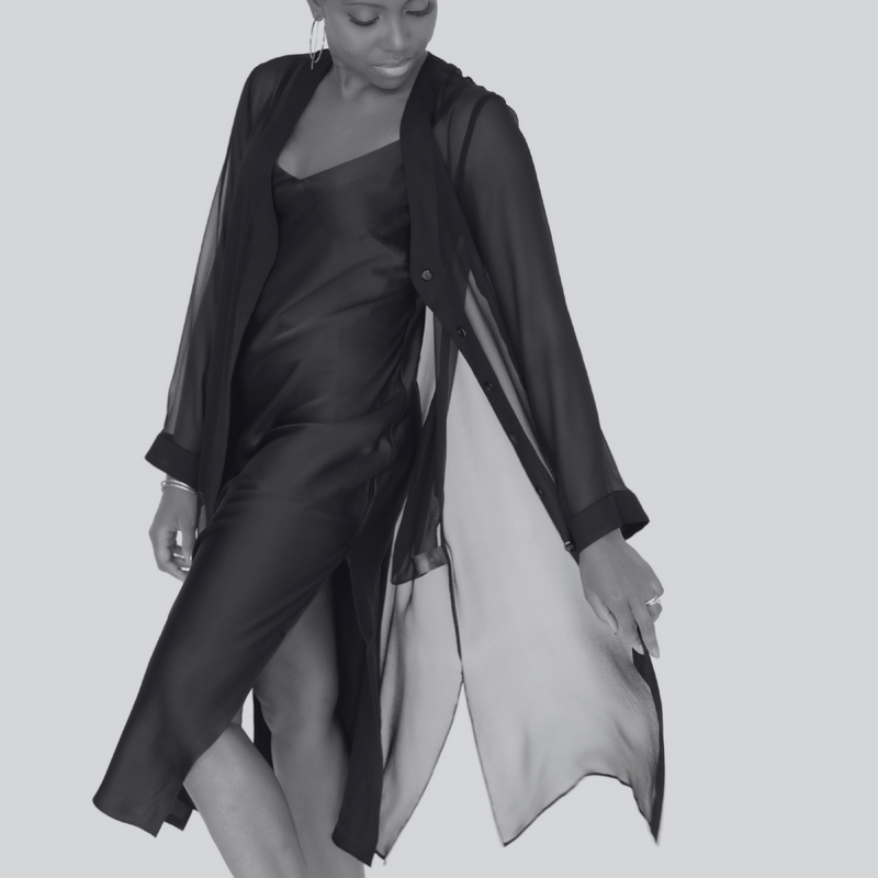 Person wearing a black and gray outfit with a sheer overlay on a light gray background