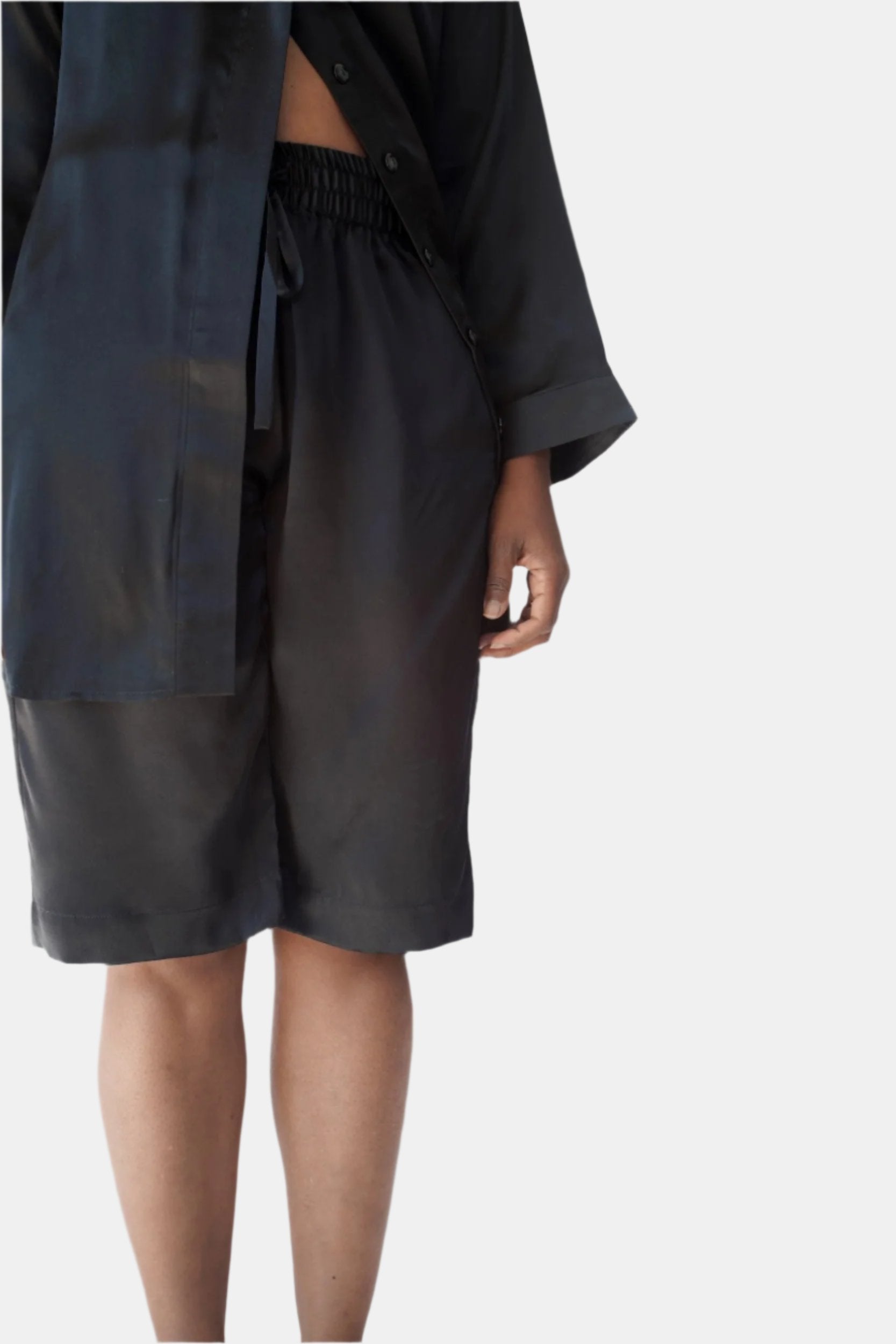 A close-up of a person wearing black silk drawstring tuxedo bermuda shorts

made in the softest washed silk charmeuse, this bermuda short has an elastic waistband and drawstring closure  wear with a je mérite coordinating top or your favorite lingerie  wide elastic waist with drawstring closure sits at natural waist  sensual fit  washed 100% silk charmeuse  designed and made in new york city, new york - available in 0/2-20/22