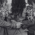 Two people embracing with bouquets of small white flowers, black and white photo