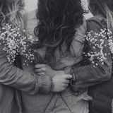Two people embracing with bouquets of small white flowers, black and white photo