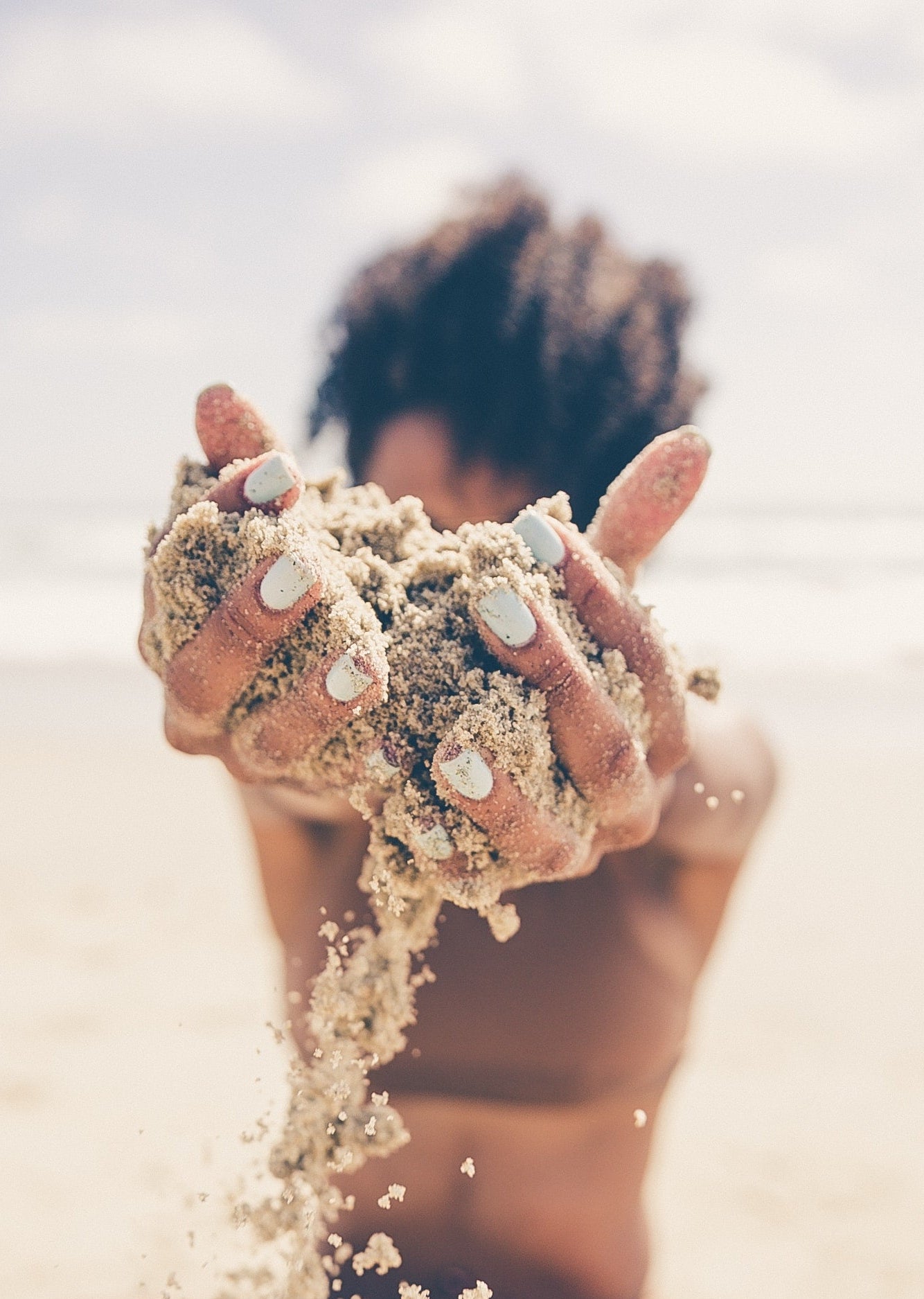 Person holding sand in their hands on a beach